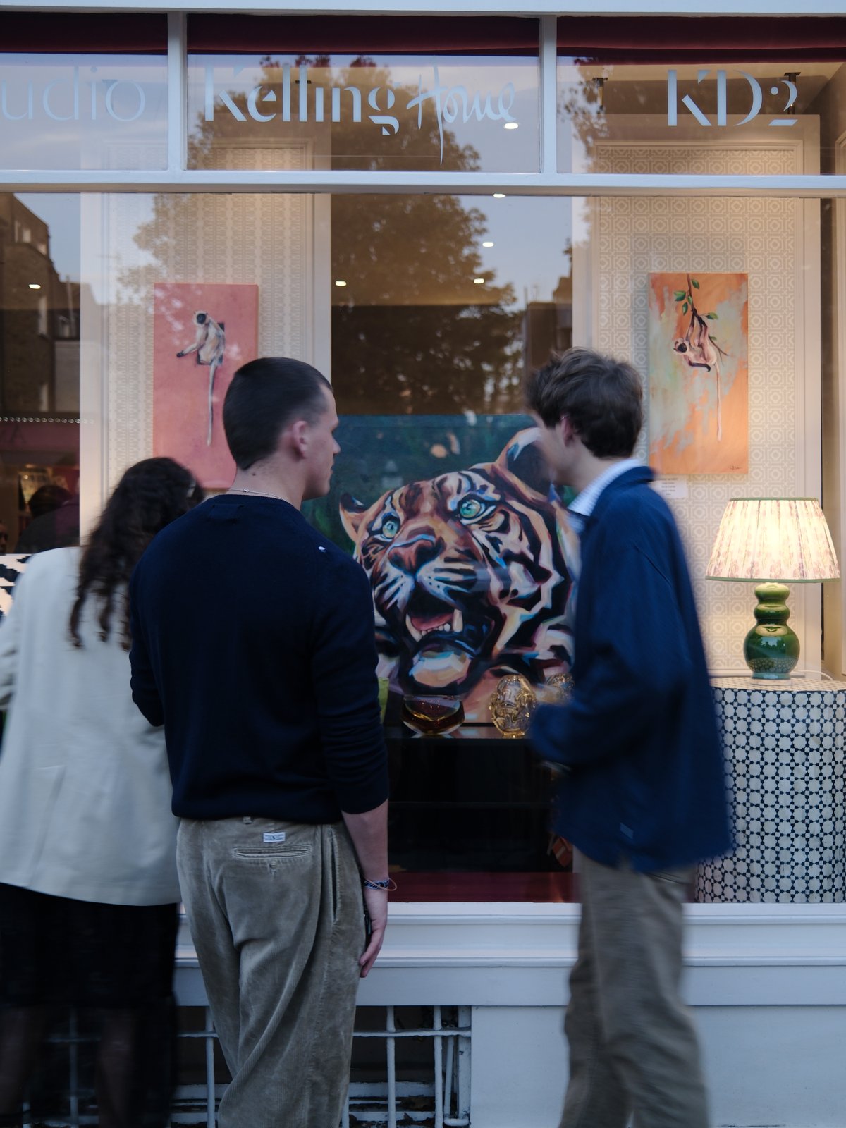 Two people looking through the Kelling Home window at a painted tiger